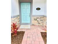 Inviting front entrance with a vibrant blue door, stone accents, and red landscaping that enhances curb appeal at 2834 Narcoossee Commons Way, St Cloud, FL 34771