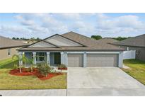 Charming single-story home with a three-car garage, landscaped yard, and a modern design under a cloudy sky at 3007 Audubon Field Dr, Bartow, FL 33830