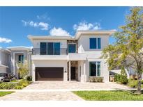 Elegant two-story home with a modern facade, a balcony, and a well-manicured front yard at 960 Jack Nicklaus Ct, Kissimmee, FL 34747