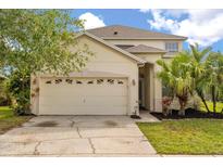 This home features a two car garage and a well-manicured lawn with mature palm trees at 529 Tuten Trl, Orlando, FL 32828