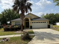 Charming yellow home with lush landscaping and a spacious two-car garage at 15824 Heron Hill St, Clermont, FL 34714