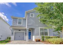 Charming two-story home with a blue door, a gray garage door, and landscaped front yard at 1628 Moon Valley Dr, Davenport, FL 33896