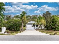 Inviting single-story home with a private driveway, a two-car garage, and mature trees under a cloudy sky at 19261 Quarterly Pkwy, Orlando, FL 32833