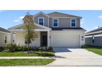 Two-story home with neutral stucco, stone accents, a two-car garage and freshly landscaped lawn at 640 Trotters Dr, Eagle Lake, FL 33839