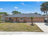 Charming single-story home featuring a tidy lawn and a two-car garage, all under a sunny blue sky at 8720 Larwin Ln, Orlando, FL 32817