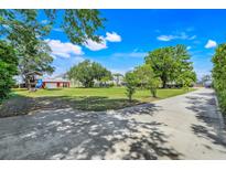 Expansive yard with lush greenery, mature trees, play structure, and a long driveway at 4570 Chambliss Rd, Winter Haven, FL 33884