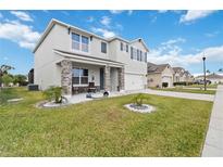 Two-story home with stone-accented columns, covered porch, well-manicured lawn, and bright blue sky at 828 Sheen Cir, Haines City, FL 33844