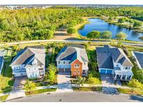 Beautiful aerial view of three homes on a sunny day, with a pond and lush green trees behind them at 9254 Reymont St, Orlando, FL 32827