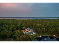 An aerial view of an estate with a beautiful surrounding forest and lake at twilight at 11450 Nellie Oaks Bnd, Clermont, FL 34711