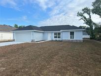 Charming single-story home featuring a fresh blue exterior, attached garage, and professionally landscaped front yard at 13075 Se 35Th Ct, Belleview, FL 34420