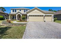 Stunning two-story home with a three-car garage, paver driveway and walkway, and beautifully landscaped front yard at 3428 Deer Oak Cir, Oviedo, FL 32766