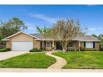 Charming single-story brick home with a well-manicured lawn and mature tree in a quiet neighborhood at 528 Woodview Dr, Longwood, FL 32779