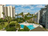 A scenic view of the inviting pool area surrounded by lush tropical landscaping and buildings on a sunny day at 6165 Carrier Dr # 3602, Orlando, FL 32819