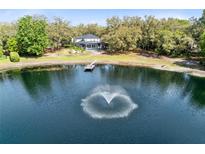 Expansive property features a private lake with fountain, lush landscaping, and a charming home with screened porch at 835 Dyson Dr, Winter Springs, FL 32708