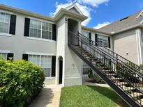 Attractive condo exterior with black shutters, green grass, and black railing up the stairs at 9021 Lee Vista Blvd # 1707, Orlando, FL 32829