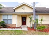 Charming home featuring a brick facade, well-manicured landscaping, and a striking red front door at 321 Moffat Loop, Oviedo, FL 32765
