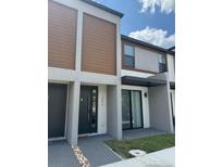 Modern townhome with neutral tones, wooden accents, and stylish front door at 3296 Tranquil Trl, Kissimmee, FL 34747