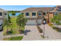 Inviting two-story townhome featuring a brick driveway, attached two-car garage, and well-maintained lawn at 1969 Portofino Meadows Blvd, Orlando, FL 32824