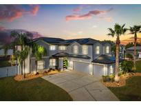 Stately home with three-car garage, manicured landscaping and tall palm trees at sunset at 3209 Waterbridge Ct, Kissimmee, FL 34744