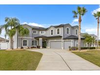 Elegant gray two-story home with a spacious driveway and lush lawn and palm trees under a sunny sky at 3209 Waterbridge Ct, Kissimmee, FL 34744
