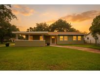 Charming single-story home with a cozy front porch and a well-maintained green lawn at sunset at 4385 Cassius St, Orlando, FL 32811