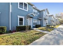 A vibrant blue townhome showcases manicured lawns, sidewalks, and classic architectural details at 534 Wilton Cir, Sanford, FL 32773
