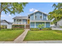 Charming blue two-story home featuring a yellow door, a welcoming front porch, and lush landscaping at 417 Barclay Ave, Altamonte Springs, FL 32701