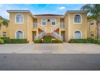 Attractive two-story condo with a yellow exterior, red tile roof, white stair railings, and well-maintained landscaping at 5201 Lake Marion Golf Resort # 5201, Kissimmee, FL 34759