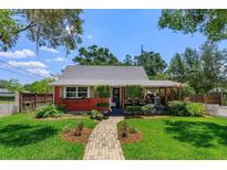 Charming red single-story home with inviting brick pathway and well-manicured lawn, blending curb appeal and comfort at 1010 N Clayton St, Mount Dora, FL 32757