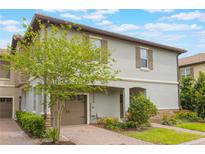 Two story house with a two car garage and an arched entryway surrounded by lush landscaping at 1312 Shinnecock Hills Dr, Davenport, FL 33896