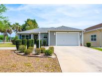 Charming single-story home featuring a well-manicured front yard with lush landscaping and a two-car garage at 1329 Paradise Dr, Lady Lake, FL 32159