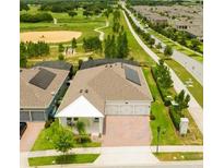 Beautiful aerial view of a home with solar panels in a golf community with a three-car garage and brick paved driveway at 14711 Winter Stay Dr, Winter Garden, FL 34787