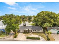 Lakefront home showcases stylish gray brick, mature landscaping, and a private dock for waterfront enjoyment at 201 Cedarwood Dr, Maitland, FL 32751