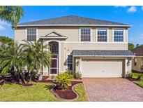 Charming two-story home features a manicured front yard, brick driveway, and an attached two-car garage at 2081 The Oaks Blvd, Kissimmee, FL 34746