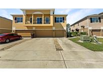Three-story townhome featuring an attached garage and well-manicured landscaping and a red car out front at 2124 Betsy Ross Ln, St Cloud, FL 34769