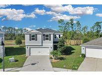 Charming two-story home featuring a two-car garage, well-manicured lawn, and lush landscaping at 216 Miles Ct, Davenport, FL 33837