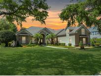 Beautiful one story home featuring a well manicured lawn, stone accents, and decorative palm trees at 6110 Keenes Pointe Dr, Windermere, FL 34786
