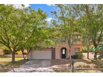 Charming two-story home with a well-maintained lawn and mature trees providing shade and curb appeal at 1037 Sailing Bay Dr, Clermont, FL 34711