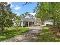 Stunning exterior of home featuring a covered portico, long driveway, and mature trees at 1417 Olympia Ave, Mount Dora, FL 32757