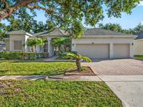 Charming single-story home featuring lush landscaping and a brick-paved driveway leading to a three-car garage at 1551 Sherbrook Dr, Clermont, FL 34711