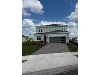 Charming two-story home features a gray exterior, paver driveway, and well-manicured landscaping at 8243 Fenton St, Orlando, FL 32836