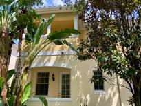 Two-story home with neutral colors, a balcony, and lush tropical landscaping in front at 8639 Lower Villagewalk Cir, Orlando, FL 32827