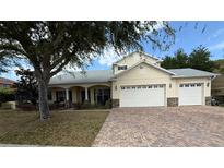 Charming exterior of home featuring a manicured lawn, brick driveway, and a two car garage at 12238 Still Meadow Dr, Clermont, FL 34711