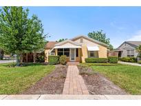 Charming single-story home with a manicured lawn, brick pathway, and awnings over windows at 335 W Bay St, Winter Garden, FL 34787