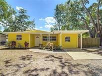 Charming yellow single-story home featuring a covered porch, manicured lawn, and mature trees at 3600 Merryweather Dr, Orlando, FL 32812