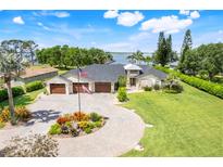 Stunning waterfront home featuring a three-car garage, circular driveway, lush landscaping, and picturesque water views at 3640 Crump Rd, Winter Haven, FL 33881