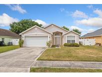 Charming single-story home featuring an attached two-car garage, well-maintained lawn, and neutral-toned facade at 3830 Spring Breeze Dr, Orlando, FL 32829