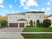 Elegant two-story home with a manicured lawn, a three-car garage, and a stone-accented facade at 645 American Holly Pl, Oviedo, FL 32765