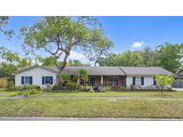 Charming single-story home with lush landscaping, mature trees, and blue shutters at 801 Fox Valley Dr, Longwood, FL 32779