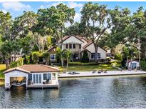 Aerial view of the property with a two-story home, boathouse with lift, and lakefront beach area at 805 W 2Nd Ave, Windermere, FL 34786